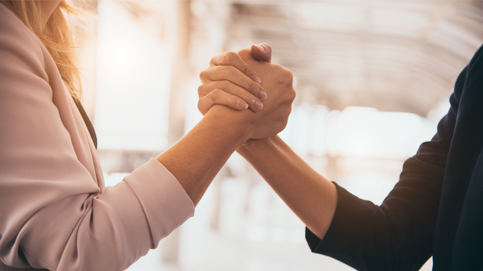 Two female businesswomen shaking hands and showing trust